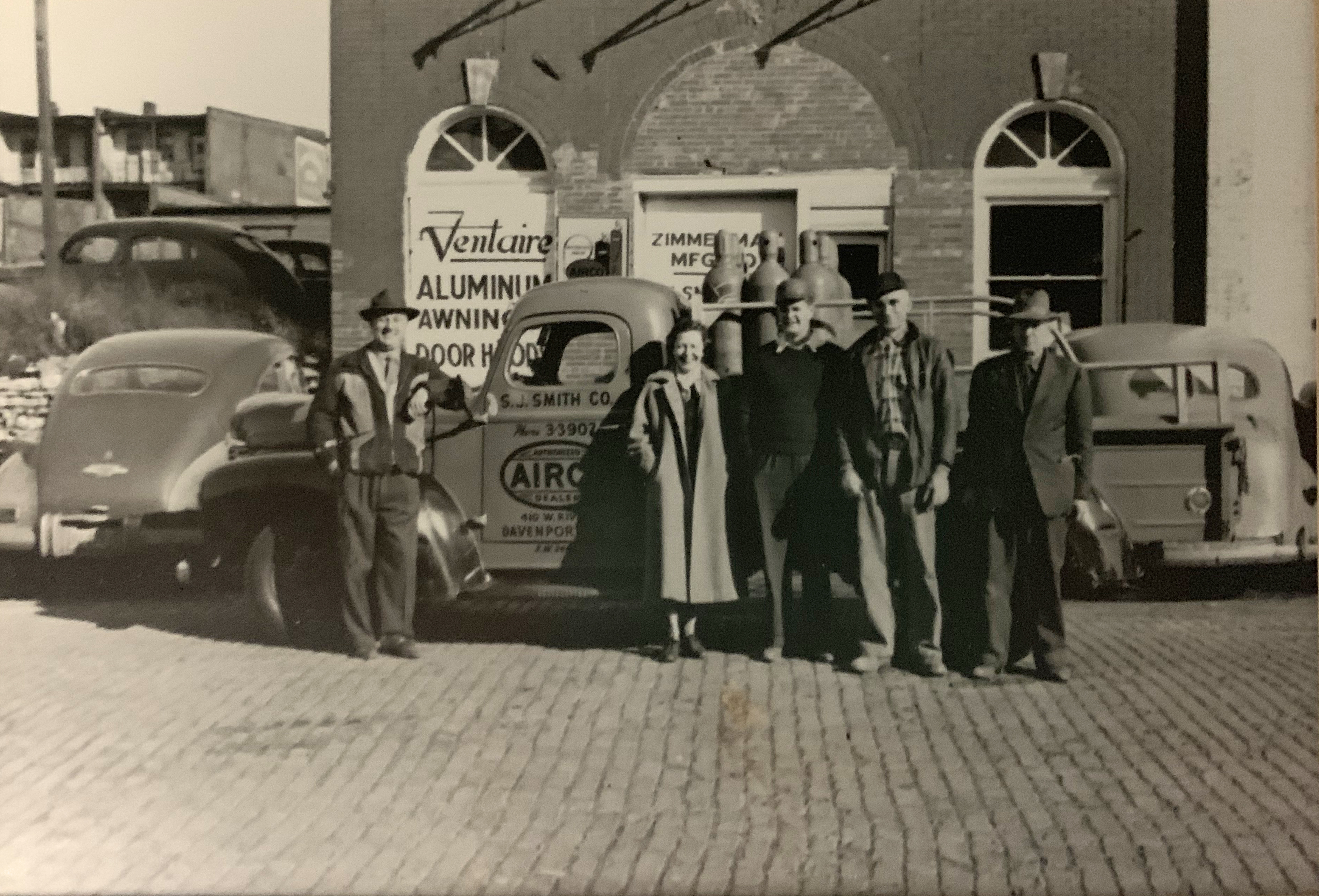 Sylvester "S.J." and Helen Smith, employees, building owner, in front of 1950s S.J. Smith building, truck.